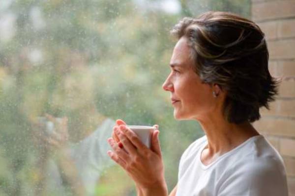 Woman relaxing with a hot drink by a window